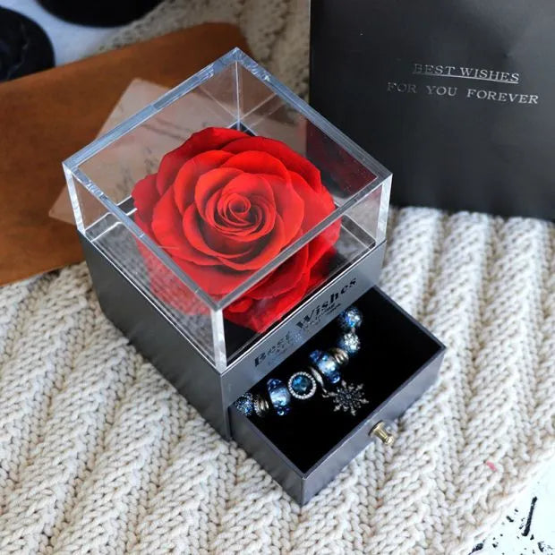 Blue and pink eternal flower gift box with roses and carnations on a table.