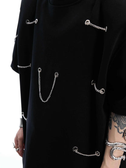 Black padded shoulder T-shirt with metal chain detail on model, showing short sleeves and round neck.