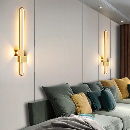 Round black iron wall sconce with integrated LED light glowing on a modern grey wall