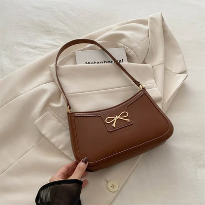 Western style shoulder bag with bow detail in rose pink colour, showing horizontal square shape and single strap.