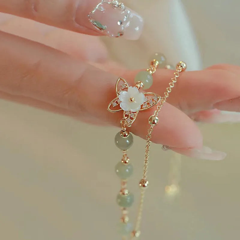 Women's shell flower butterfly bracelet in yellow gold with geometric design and hetian jade style charm.