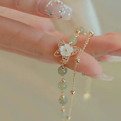 Women's shell flower butterfly bracelet in yellow gold with geometric design and hetian jade style charm.