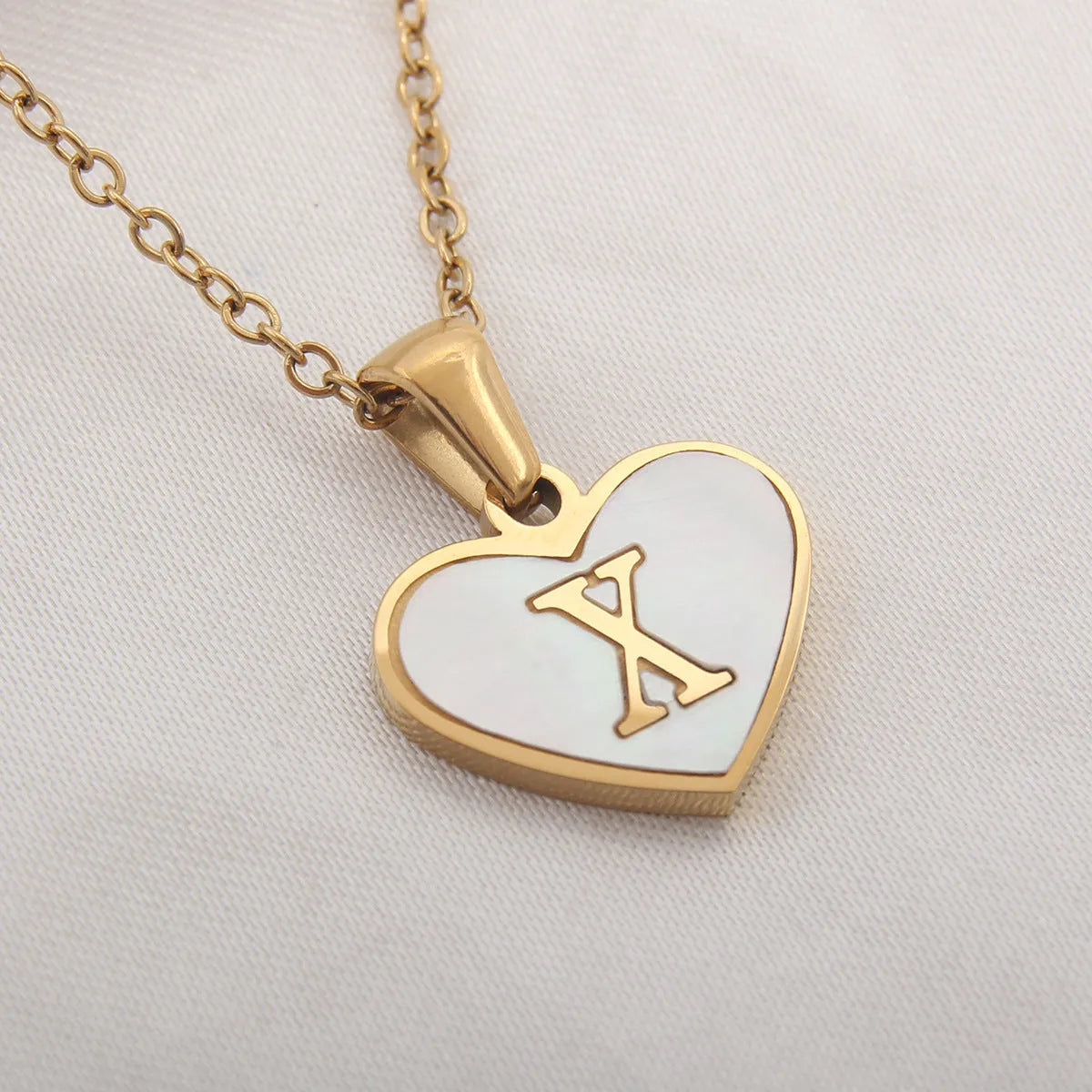 Gold-plated clavicle necklace with a white shell heart pendant, personalised with a letter from A to Z.