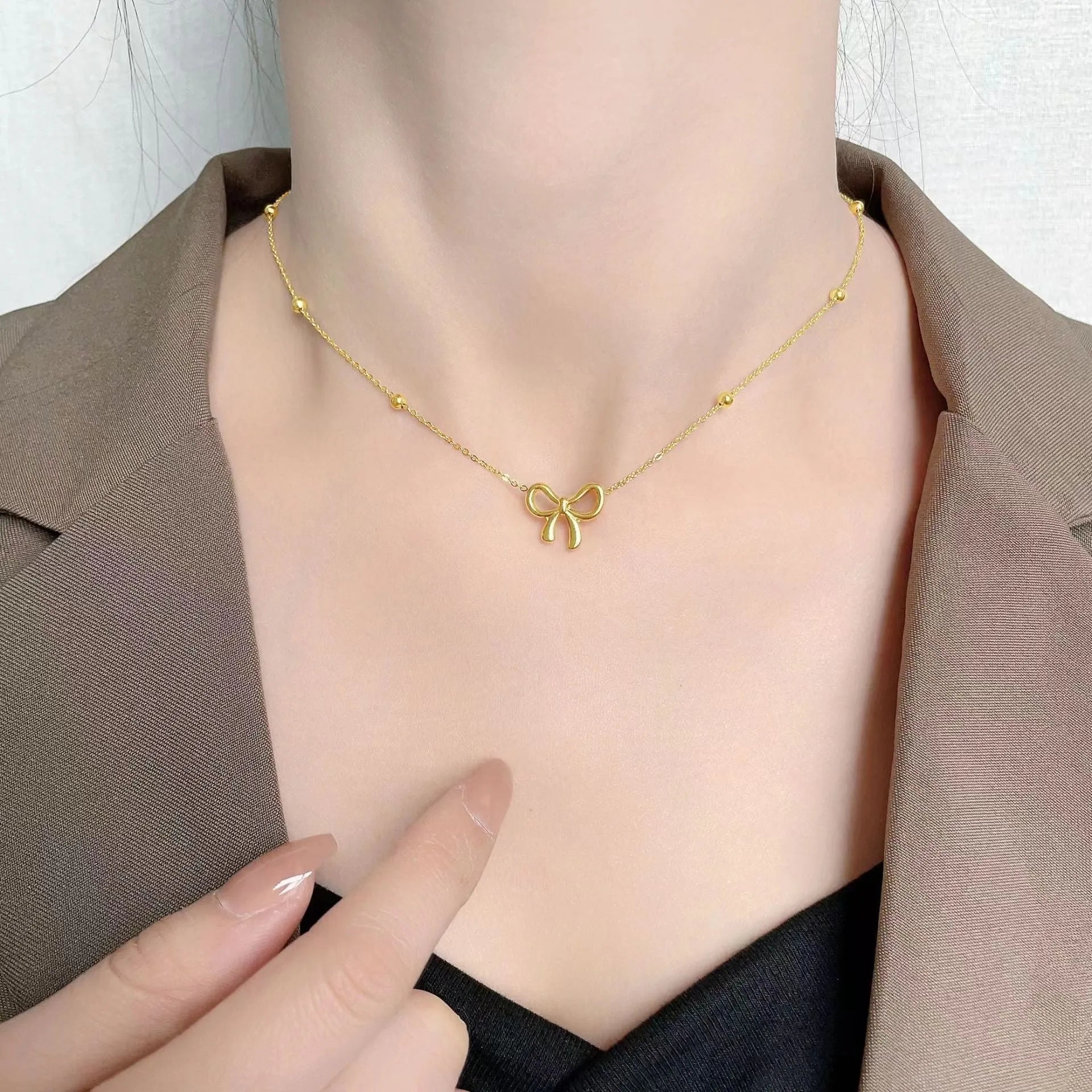 Gold titanium steel necklace with bow pendant on an adjustable cross chain, length 41cm to 50cm.