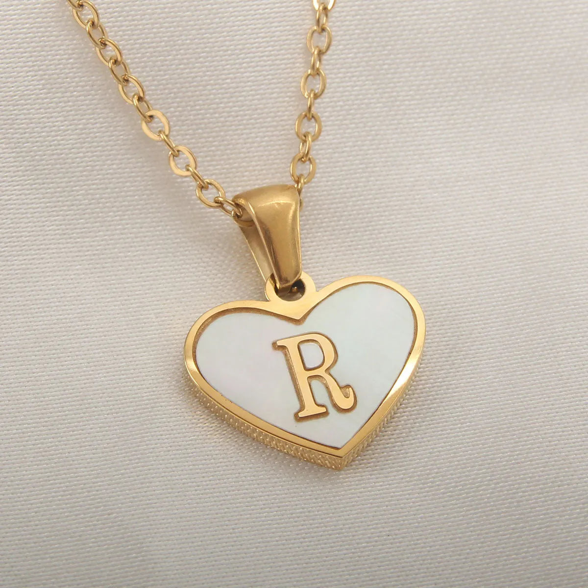 Gold-plated clavicle necklace with a white shell heart pendant, personalised with a letter from A to Z.