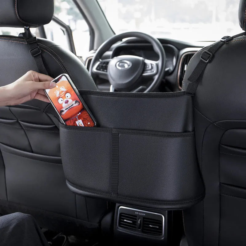 Black leather car seat gap storage bag with carbon fibre pattern, shown between car seats.