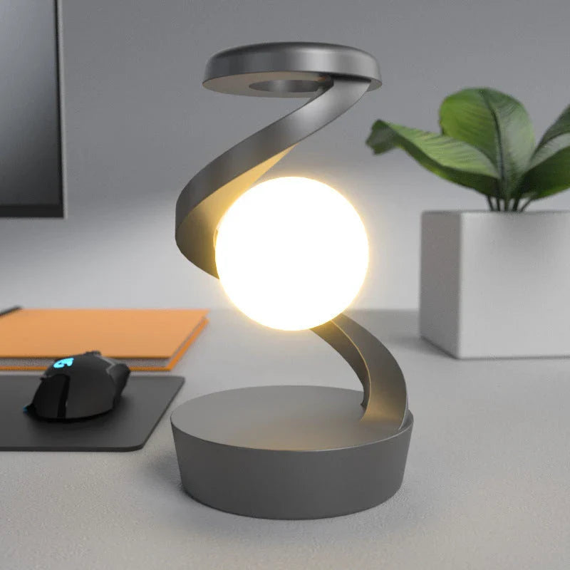 A rotating moon-shaped desk lamp with a wireless charging pad for smartphones, featuring a sleek and modern design.
