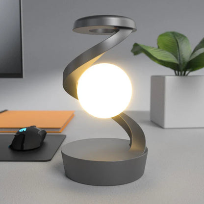 A rotating moon-shaped desk lamp with a wireless charging pad for smartphones, featuring a sleek and modern design.