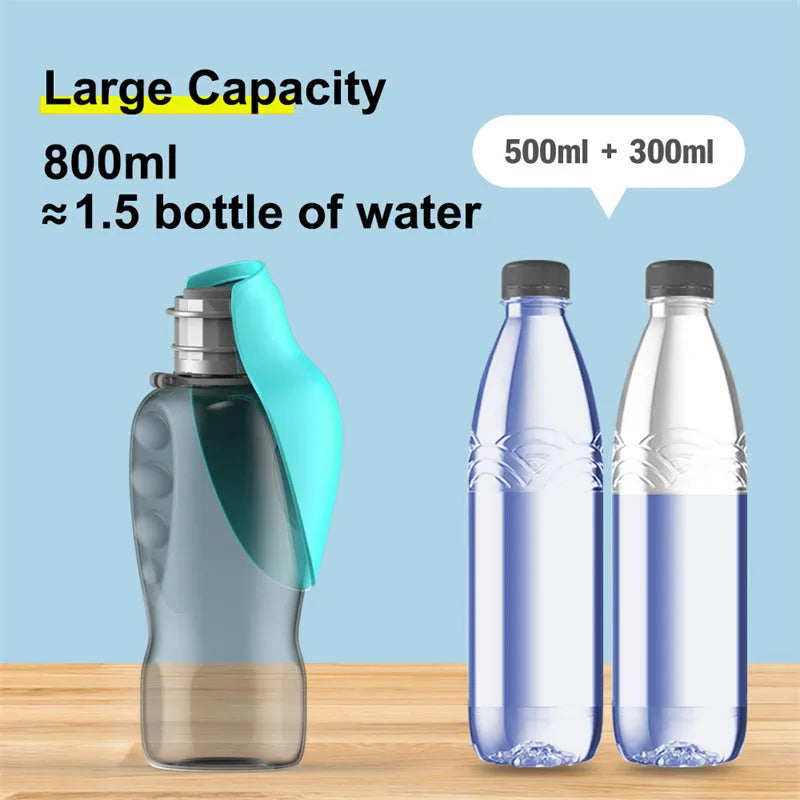 Blue grey portable dog water bottle with foldable drinking bowl and wrist strap, shown next to a dog.