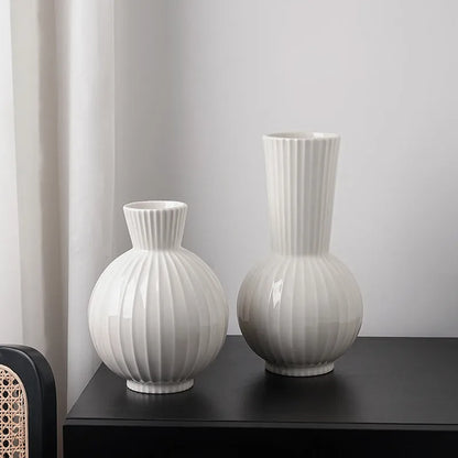 White ceramic ball-shaped vase with striped pattern, shown in small and large sizes with orchid arrangements