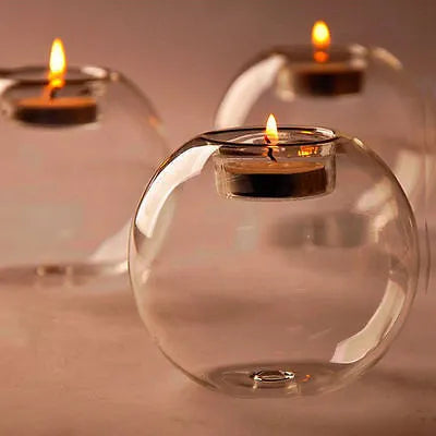 Handmade round hollow glass candle holder in three sizes on a table.
