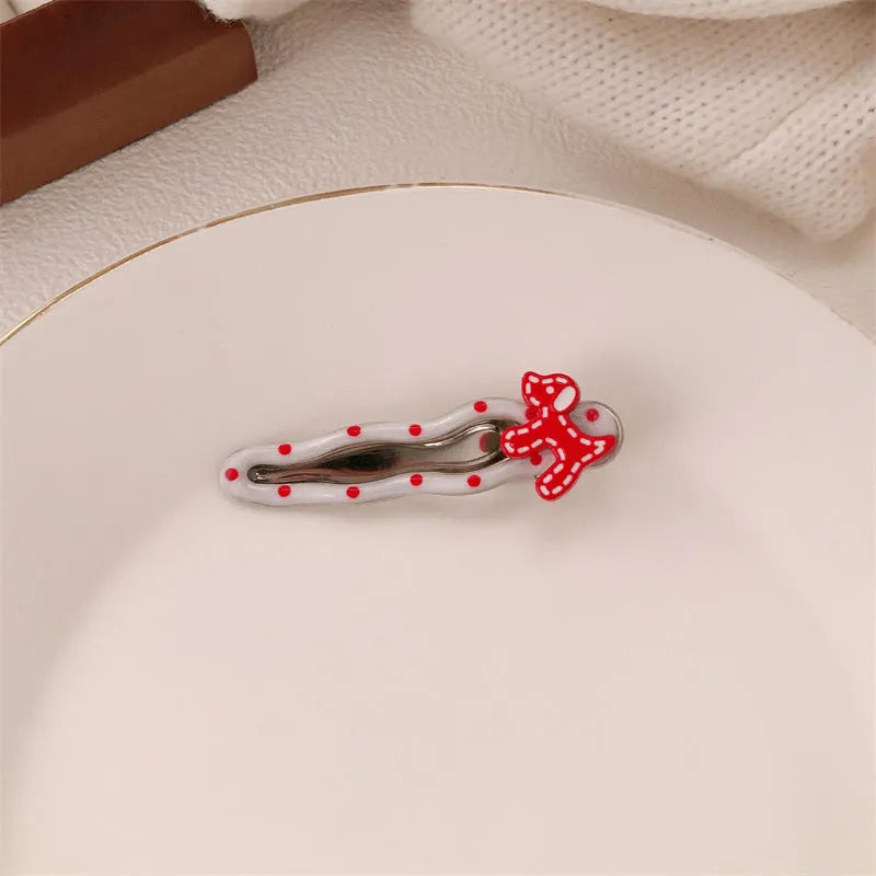 Red plastic hair clip with a 3D love heart and dots on a willow leaf-shaped base.