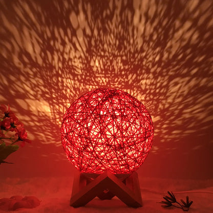 Spherical hand-knitted rattan table lamp with remote control on a wooden desk