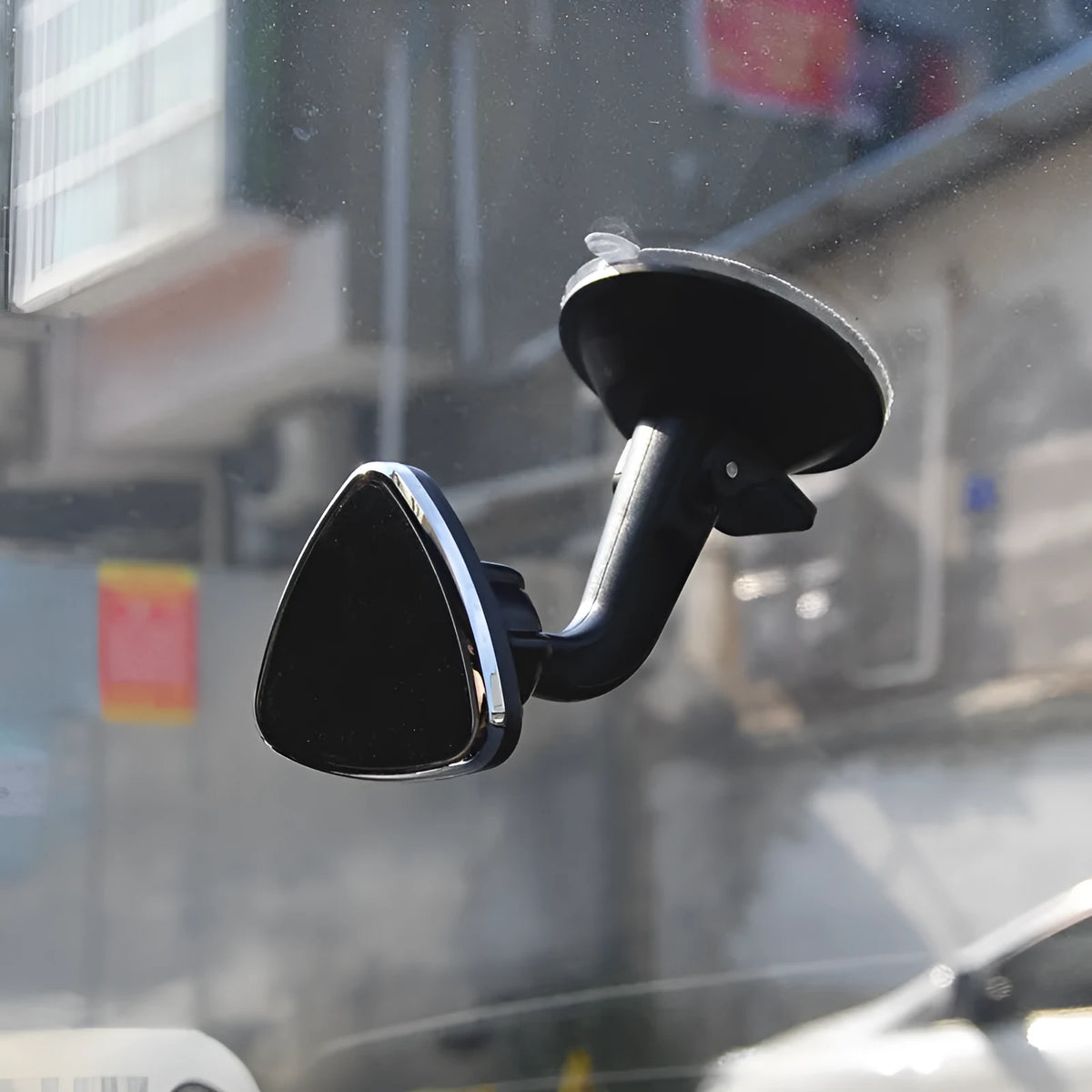 Classic black magnetic car phone holder mounted on a car dashboard, showing a smartphone attached.