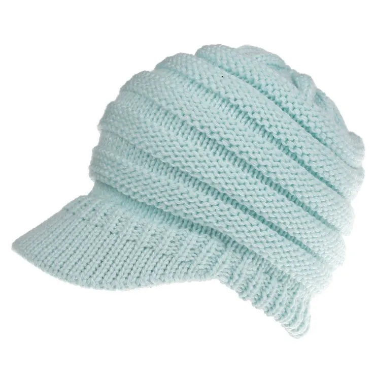 Woman wearing a light grey knitted ponytail beanie with her ponytail pulled through the hole in the back.