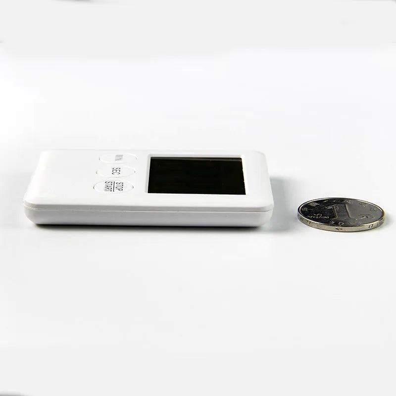 Black and white metal kitchen timer with magnetic back on a refrigerator door