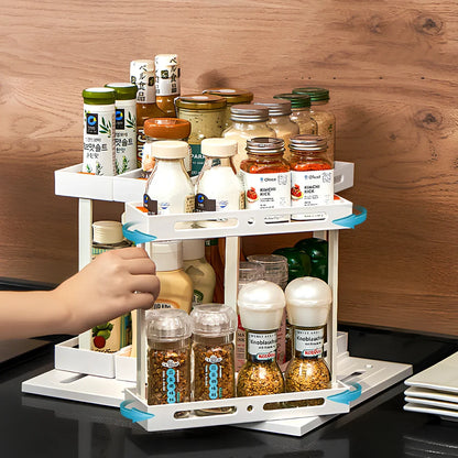 Pull-out spice rack installed under kitchen sink with spices organised in plastic drawer