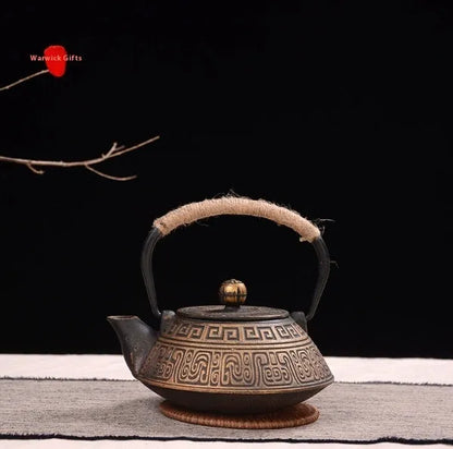 Japanese-style cast iron teapot with lid on a hob, shown in a bronze finish.