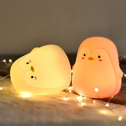White silicone penguin-shaped USB rechargeable night light on a surface.
