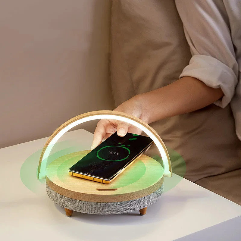 Wireless charging LED night light with Bluetooth speaker in marble pattern finish on a wooden desk.