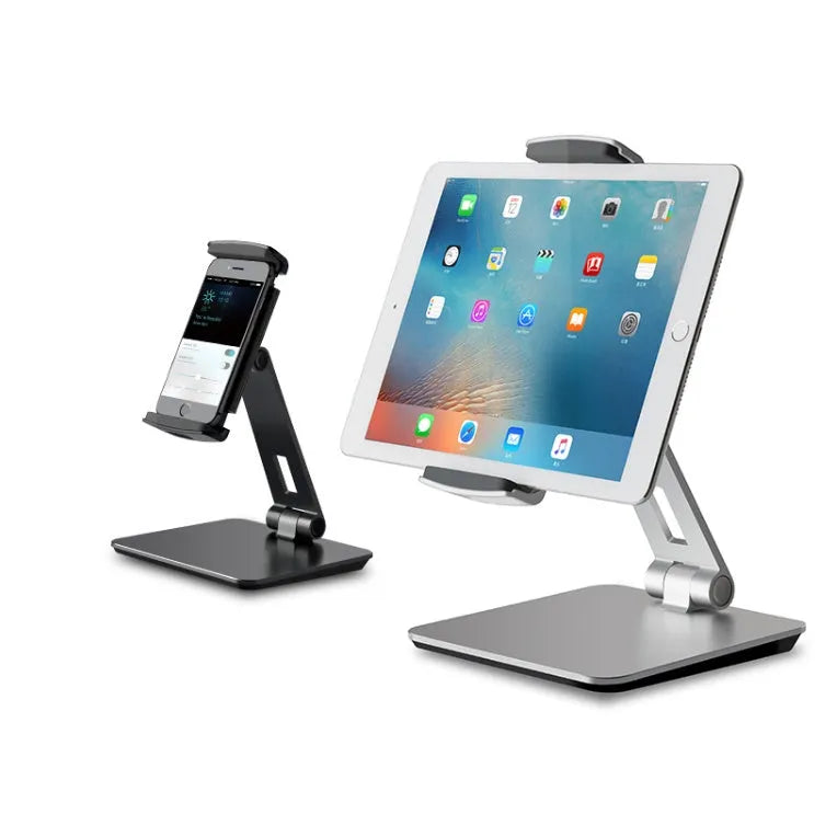 Silver foldable aluminium phone and tablet holder on a wooden desk, showing 360-degree rotation and silicone pads.