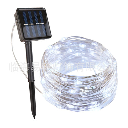 Solar-powered LED string lights arranged in garden with solar panel charging in sunlight