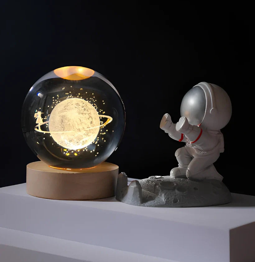 3D crystal ball night light projecting solar system pattern on wooden base with astronaut figurine