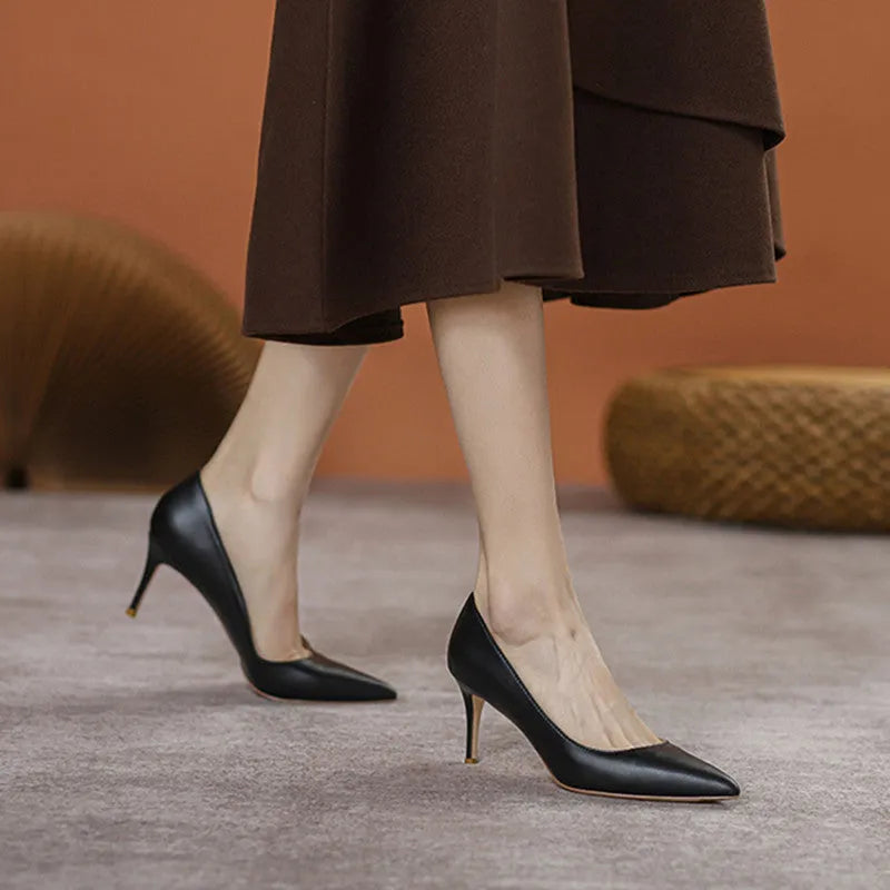 Black pointed toe stiletto high heel shoe with a low cut vamp on a white background.