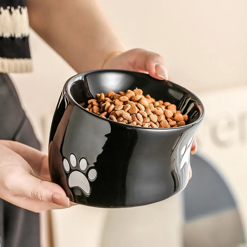 Ceramic cat bowl with high foot and cat's paw base in an oblique mouth design.