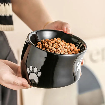 Ceramic cat bowl with high foot and cat's paw base in an oblique mouth design.
