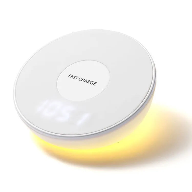 White wireless charging stand with digital clock display, showing time, next to a mobile phone on its angled charging platform.