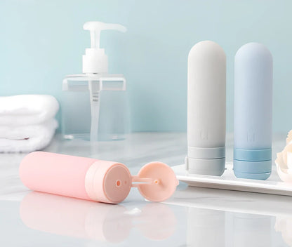 Set of three silicone travel bottles in light grey, pink, and blue colours with screw caps