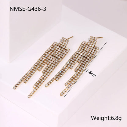 Gold-coloured women's earrings with a love heart shape, star details and dangling diamond-style tassels on a white background.
