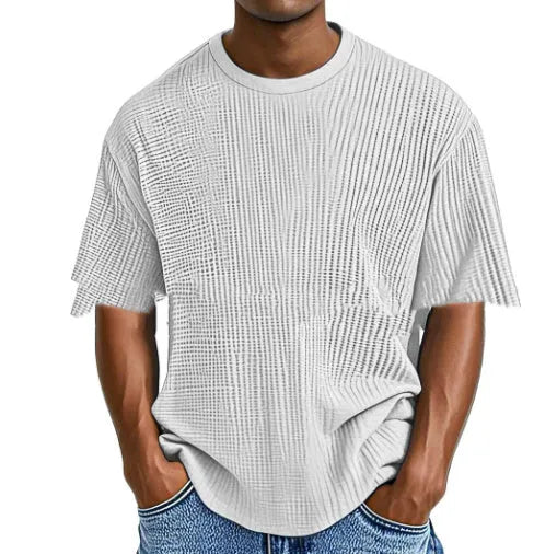Man wearing a light blue waffle-textured cotton blend short sleeve t-shirt, casual pullover style.