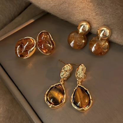 Three pairs of handmade alloy holiday earrings with geometric shapes and tassel details on display