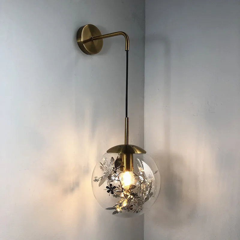 Glass wall lamp with golden flower finish and 15cm diameter, mounted beside bed with LED illumination
