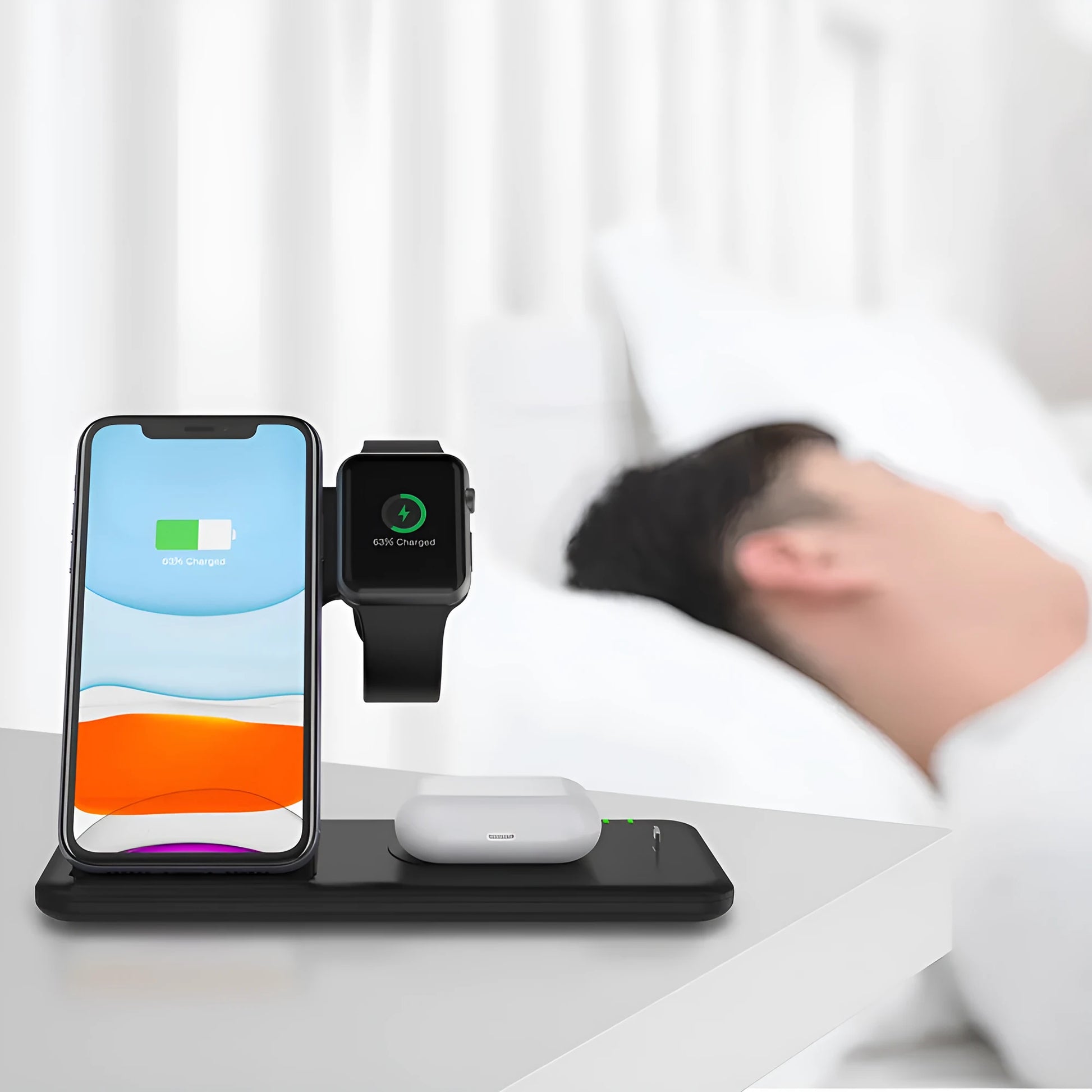 White three-in-one wireless charging stand for mobile phone, watch, and headphones on a desk.