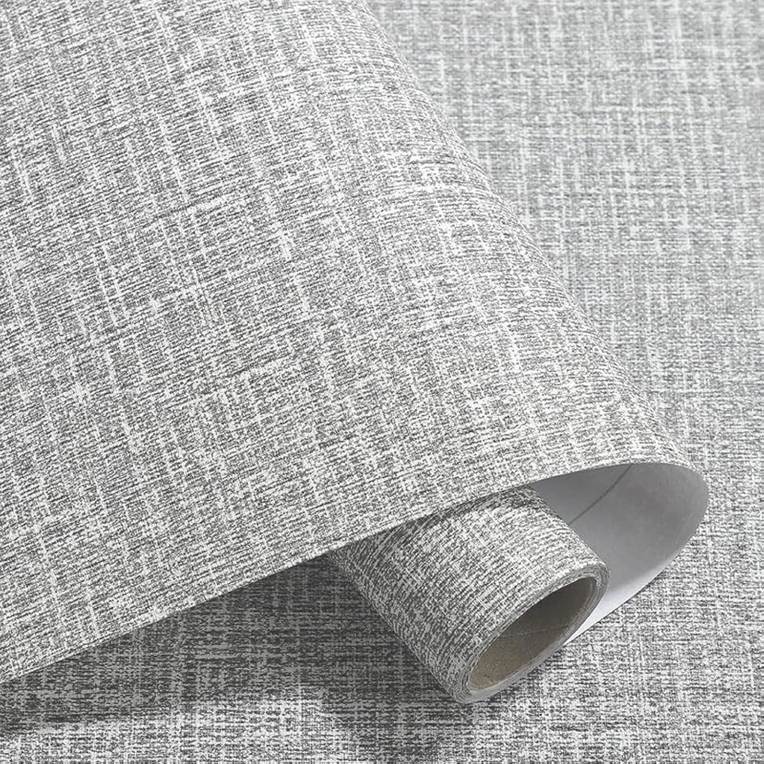Close-up of linen-textured self-adhesive wallpaper roll in beige colour, showing peel-off backing.