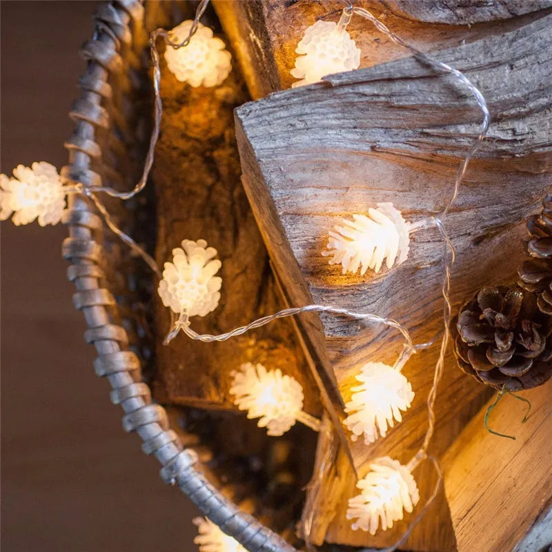 Warm white LED pine cone fairy light string on a green backdrop, showing plastic shell details.