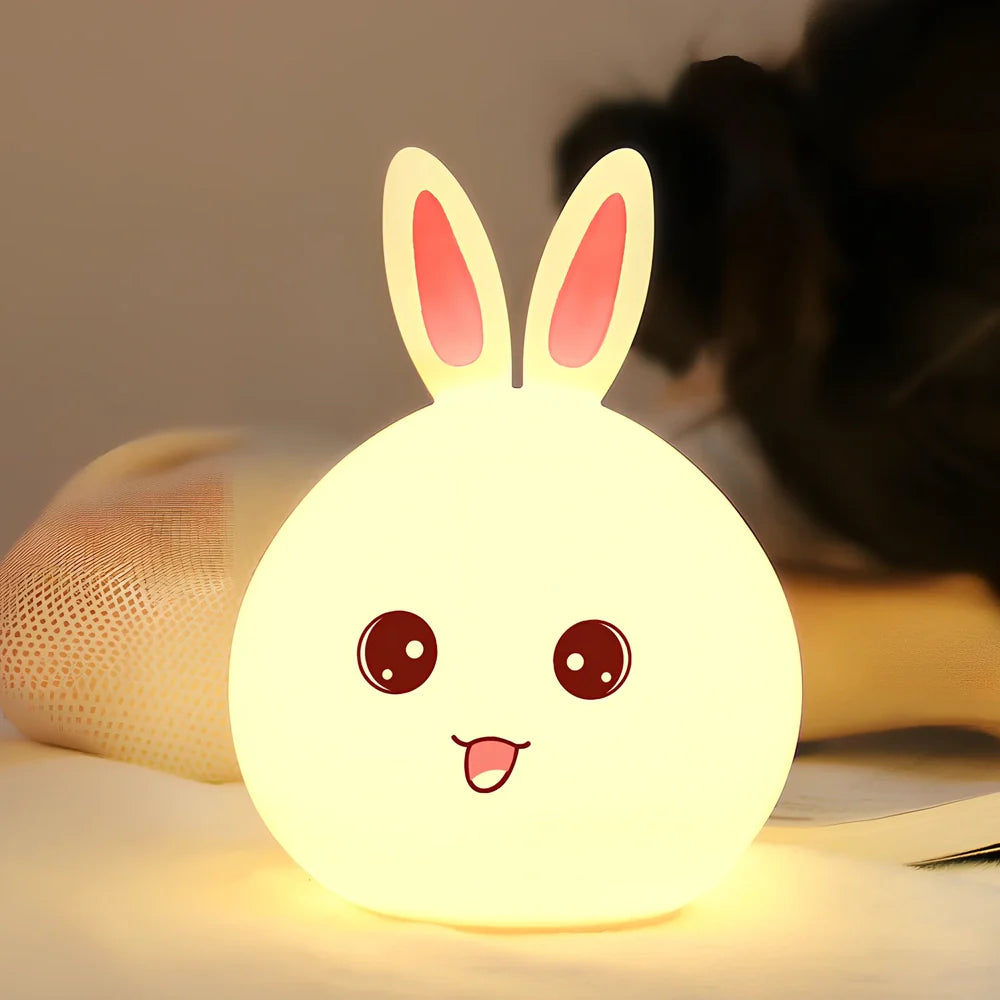 White silicone rabbit night light with USB charging cable showing touch sensor area and colourful LED illumination