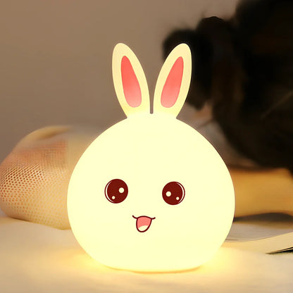 White silicone rabbit night light with USB charging cable showing touch sensor area and colourful LED illumination