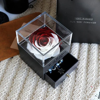 Blue and pink eternal flower gift box with roses and carnations on a table.