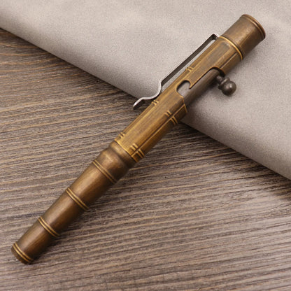 Brass tactical pen with press bolt mechanism showing cylindrical design and six ring details