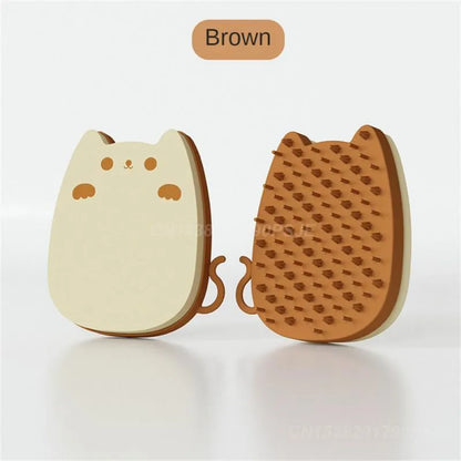 Blue silicone and sponge pet grooming brush with dual comb teeth on a wooden surface.