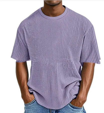Man wearing a light blue waffle-textured cotton blend short sleeve t-shirt, casual pullover style.