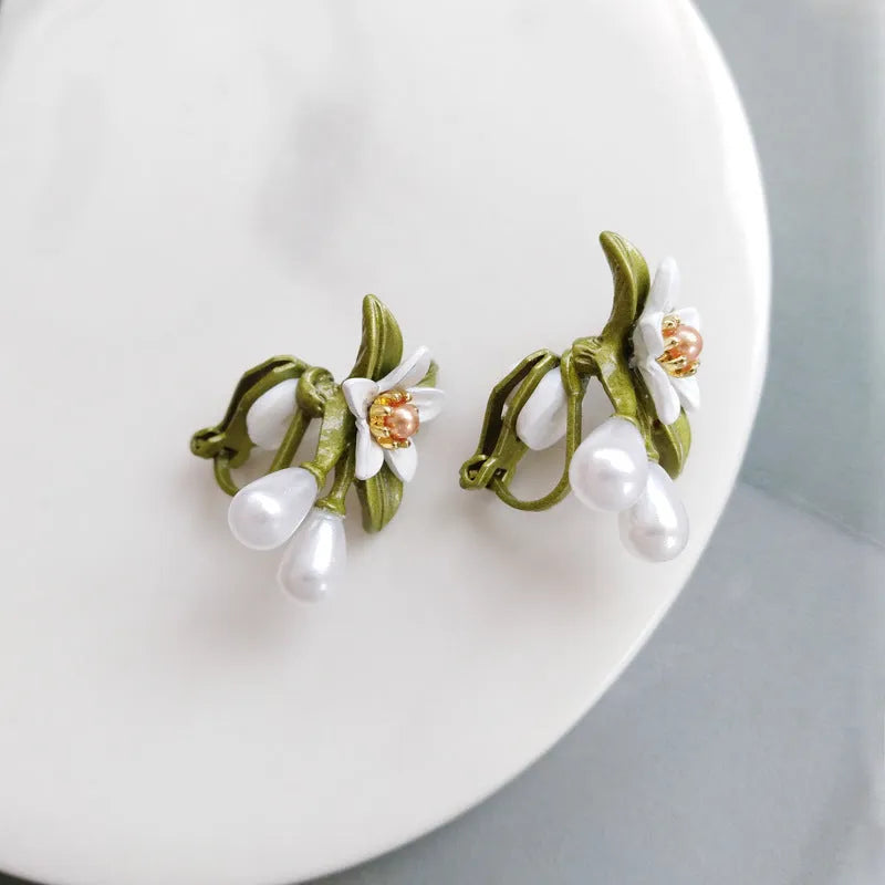 A pair of alloy flower ear studs and a pair of matching flower ear clips with a sterling silver needle detail.