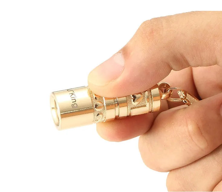 Gold electroplated waterproof mini LED keychain torch with zinc alloy body on a keyring.