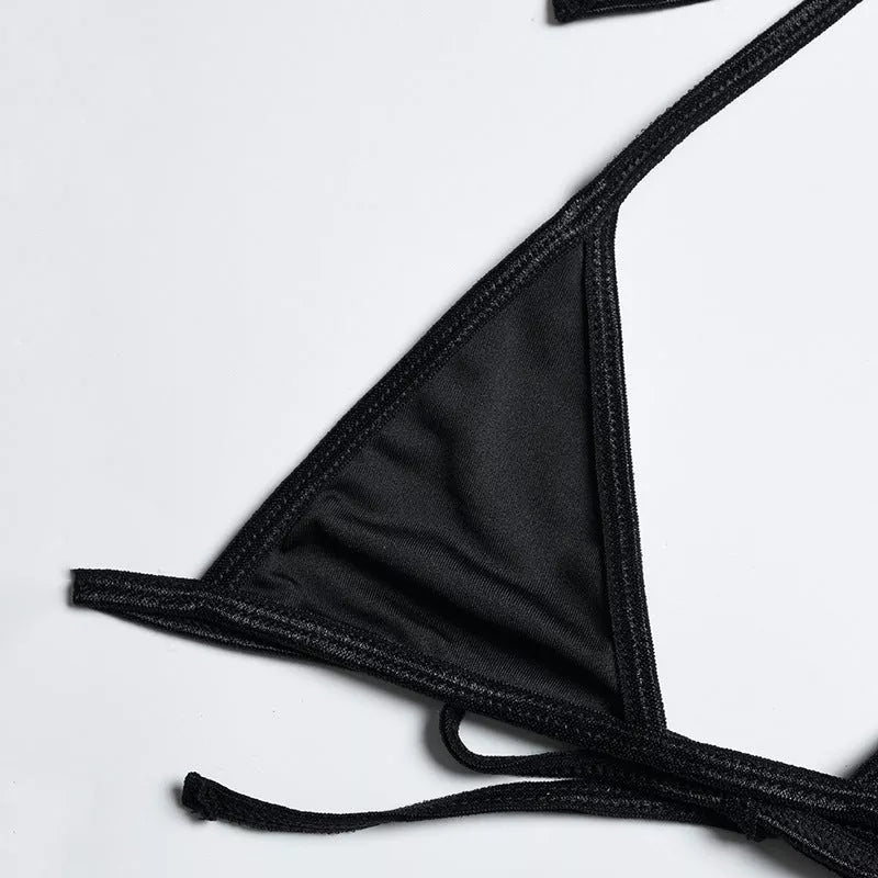 Solid black sling bikini set for women, includes bra, jacket, skirt, and shorts