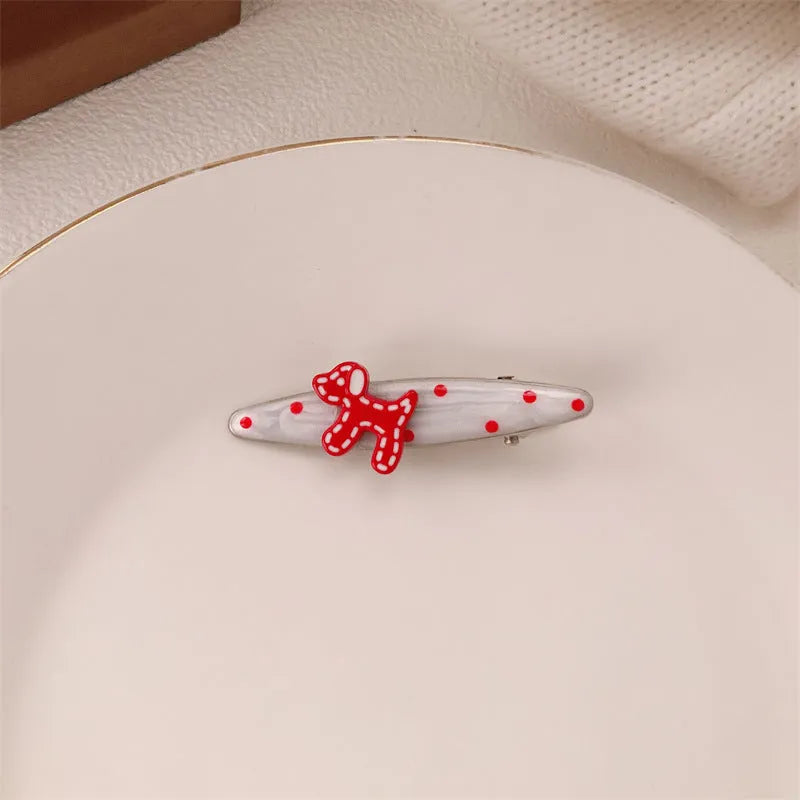 Red plastic hair clip with a 3D love heart and dots on a willow leaf-shaped base.