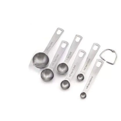 Six stainless steel measuring spoons with engraved markings and D-shape ring, sizes 1/8 tsp to 1 Tbsp
